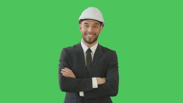 Gutaussehender lächelnder Geschäftsmann in maßgeschneidertem Anzug mit hartem Hut auf verschränkten Armen. Hintergrund ist eine grüne Bildschirm-Attrappe. — Stockvideo