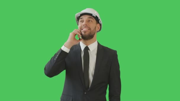 Plan moyen d'un homme d'affaires dans un chapeau dur parlant au téléphone et saluant quelqu'un. Le fond est l'écran vert . — Video