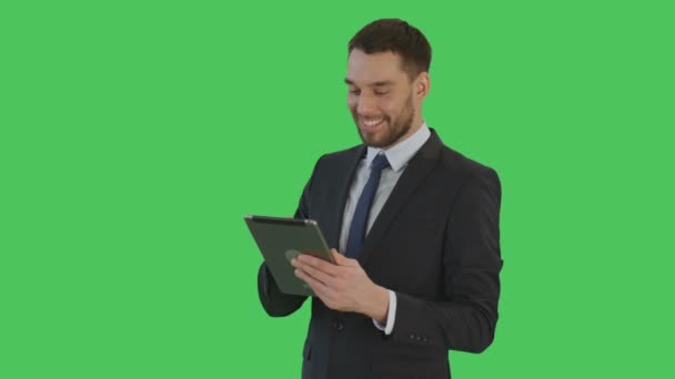 Mittlere Aufnahme eines lächelnden gutaussehenden Geschäftsmannes, der einen Tablet-Computer benutzt. Hintergrund ist Green Screen. — Stockvideo