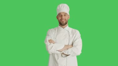 Yakışıklı bir şef kadeh orta kollarını geçerken ve gülümseyerek. Yeşil ekran arka plan olduğunu.