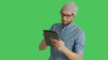 Şapka ve gözlük Tablet bilgisayar kullanarak şık bir adam orta vurdu. Yeşil ekran arka plan olduğunu.