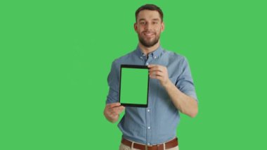 Tablet bilgisayar ile yeşil perde dikey olarak sunulması üzerinde gülümseyen bir adam orta vurdu. Arka planda yeşil ekran.