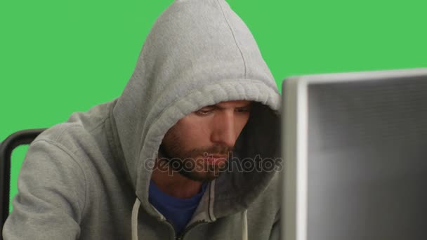 彼のデスクトップに座ってのパーカーを着ているハッカーの半ばのクローズ アップ ショット。グリーン スクリーン背景で撮影. — ストック動画