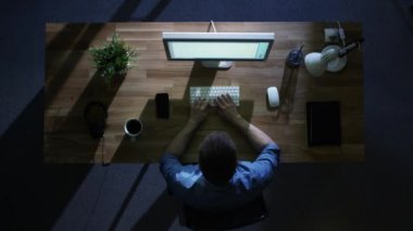 Üstten Görünüm onun masaüstü bilgisayar çalışma gece erkek programcı. Masasına soğuk mavi ışık--dan dış tarafından aydınlatılmış.