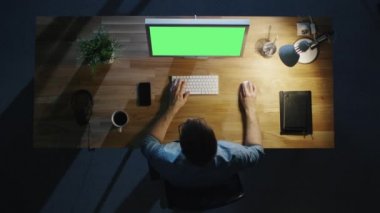 Üstten Görünüm yaratıcı adam çalışan masaüstü bilgisayarını Mock-Up yeşil ekran geceleri. Işık açıkken tablo.