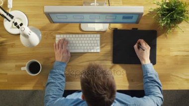 Onun masada oturan bir dijital çizim Tablet üzerinde çalışan bir genç grafik tasarımcı Üstten Görünüm. 