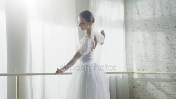 年轻和美丽的芭蕾舞演员在她足尖芭蕾鞋上优雅地跳舞。她穿着白色的短裙。工作室是现代的阳光。在慢动作. — 图库视频影像