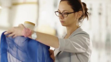 Güzel kadın moda tasarımcısı manken, çeşitli süs eşyaları ve kumaşlar üzerinde çalıştığınız terzilik ile çalışma. Onun parlak ve Sunny stüdyom.
