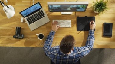 Üstten Görünüm onun masaüstü bilgisayar Tablet çizim dijital üzerine çalışan genç yetenekli fotoğrafçı. Düğün fotoğrafçılığı işleniyor. Onun çalışma alanı güneş ışığı ile kaplıdır.