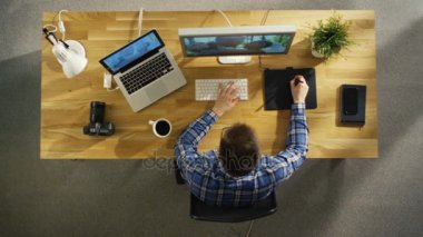 Üstten Görünüm onun masaüstü bilgisayar Tablet çizim dijital üzerine çalışan genç yetenekli fotoğrafçı. Düğün fotoğrafçılığı işleniyor. Onun çalışma alanı güneş ışığı ile kaplıdır.