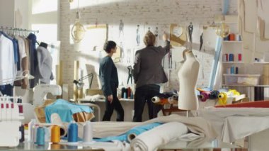 Kadın ve erkek moda seçme ve duvar giyim çizimler için onların yeni koleksiyonu için sabitleme Tasarımcısı. Sunny stüdyosudur. Renkli kumaş, giyim asılı ve dikiş öğeler görünür olur.