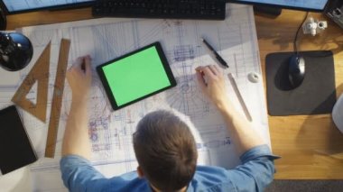 Üstten Görünüm mimari mühendis planları, kullanır Tablet bilgisayar ile yeşil perde, ile çalışma planları ile karşılaştırır. Tam olarak yararlı nesneler ve sabah güneş onun masam.
