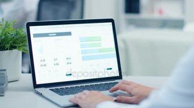 Erkek doktor okuma hastanın sağlık kartı Laptop ve yapar düzeltmeler. Modern, geniş ışık ise.