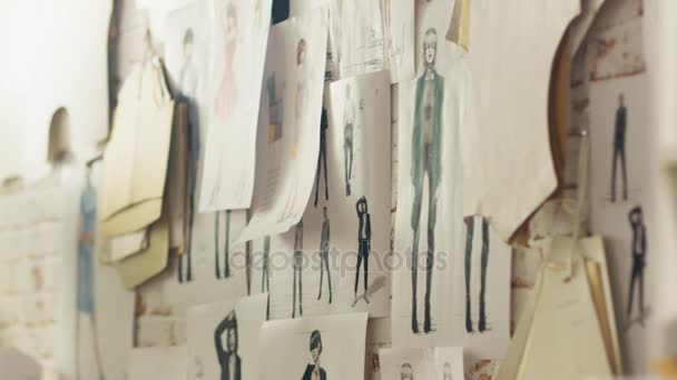 Zoom em uma parede com desenhos e esboços de moda fixados, modelos pendurados na parede . — Vídeo de Stock