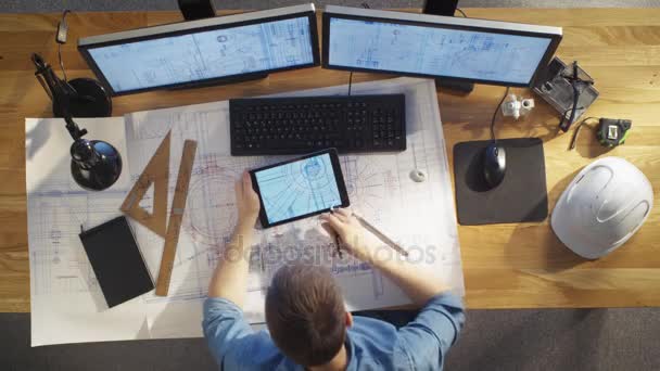 Top View of architectural Engineer Draws on His Blueprints, Compares with Tablet Computer with Green Screen, Using Desktop Computer Also. His Desk is Full of Useful Objects and Evening Sun. — Stock Video