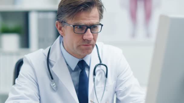 Erkek kıdemli doktor çalışma masasında — Stok video