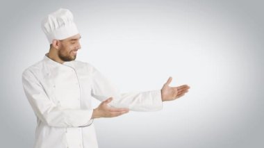 Orta bir kadeh sunan bir jest yapma ve eller bir göğüs üzerinde geçiş gülümseyen bir şef. Beyaz arka plan ile vurdu.
