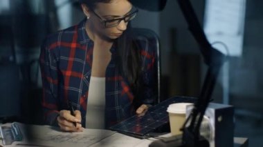 Gece geç saatlerde kadın güneş mühendis taslaklar üzerinde çalışır, güneş paneli parçası tutan ve onun kişisel bilgisayar kullanır. Boş, sadece Her masa lambası Mehtap aydınlatan Oda ise.