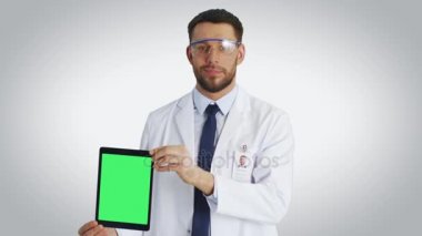 Atış bize izole Mock-up Tablet bilgisayarınızla sunulması gülümseyen bir bilim adamının orta yeşil ekran. Beyaz arka plan ile vurdu.