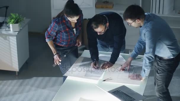 Late at Night Team of Design Engineers Trabalhe com plantas e documentos em mesa iluminada . — Vídeo de Stock
