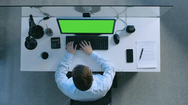Κάτοψη του επιμελής λογιστής που εργάζεται στο γραφείο του σε έναν προσωπικό υπολογιστή με πράσινη οθόνη για. Επίσης υπογράψει έγγραφα και Smartphone τοποθέτηση του πίνακα. — Αρχείο Βίντεο