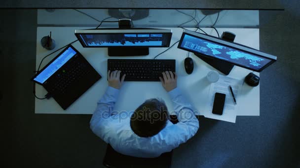 Von oben betrachtet arbeitet der Spezialist mit Tabellen und Dokumenten auf seinem Laptop und PC gleichzeitig. Stapel von Papieren auf seinem Schreibtisch. Es ist spät in der Nacht. — Stockvideo