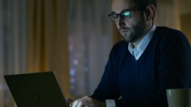 Orta yaşlı adam evde onun gözlük koyar ve bir dizüstü bilgisayar üzerinde çalışmaya başlar. Şık More'a geldi sarı tonları ve arka planda.