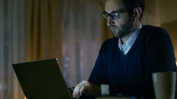 Чоловік вдома сидить на своєму столі Робота на ноутбуці. Він одягнений в окуляри, відображає їх . — стокове відео