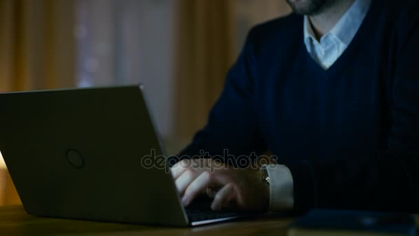 Close-up de um homem de meia-idade trabalhando em um laptop. Ele está em casa. No fundo, seu apartamento parece elegante, mas quente . — Vídeo de Stock