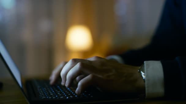 Primer plano de un hombre de mediana edad que trabaja en un ordenador portátil. Está solo en casa. La pantalla de la computadora se refleja en sus gafas. En el fondo su piso con tonos amarillos . — Vídeo de stock