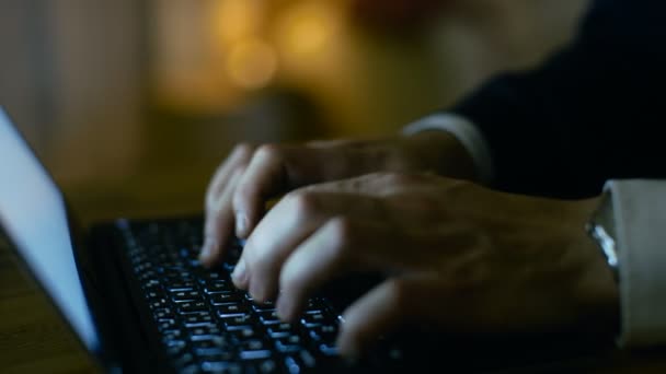 Close-up de um homem de meia-idade trabalhando em um laptop. Ele está sozinho em casa. Tela do computador reflete em seus óculos. No fundo seu apartamento com tons amarelos . — Vídeo de Stock