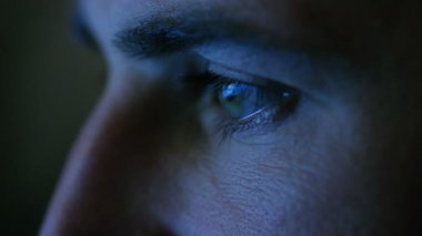 Ekran içinde yansıtan ile bir yeşil-mavi adamın gözlerini close-up. Farklı renklerle aydınlatılır.