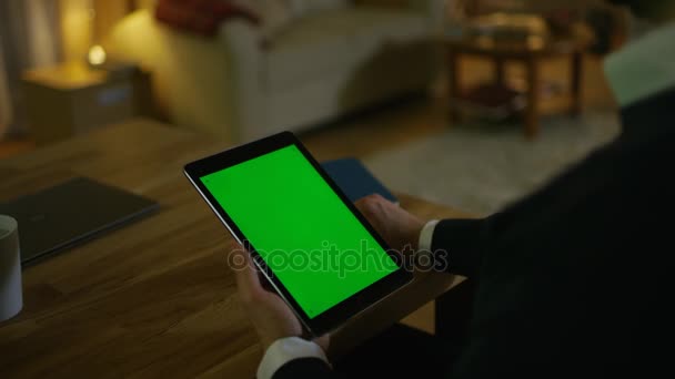 A Home ember ül a pult és a tábla-PC tartja Green Screen rajta. A lakásban történik, sárga színben és meleg. — Stock videók