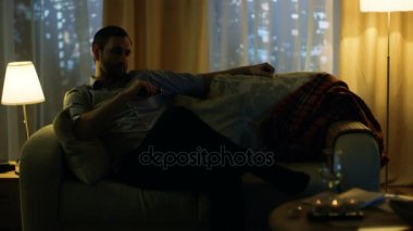 Akşam ortada, televizyonun bir kanepede oturan yaşlı adam kanalları ile uzak değiştirir. Büyük bir şehirde gökdelenler ile arka plan Windows görünüm.