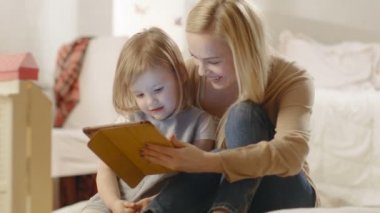 Güzel anne ve küçük kızı iyi zaman okuma çocuk kitapları bir Tablet bilgisayarda var.