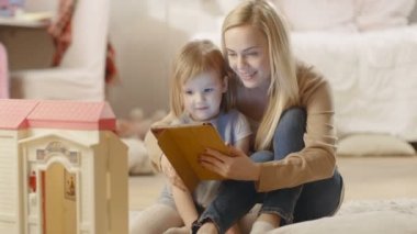 Güzel anne ve küçük kızı iyi zaman okuma çocuk kitapları bir Tablet bilgisayarda var.