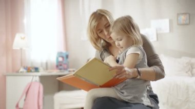 Sevimli küçük kız büyükannesinin kucağına oturur ve onlar çocuk kitabı okumak. Ağır çekim.