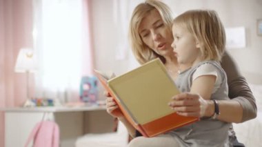 Sevimli küçük kız büyükannesinin kucağına oturur ve onlar çocuk kitabı okumak. Ağır çekim.