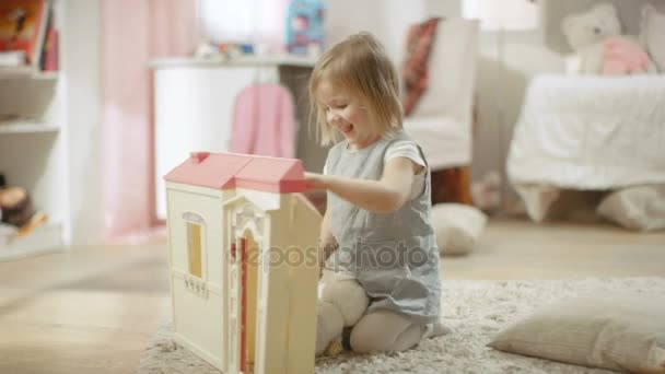 Bonne petite fille court vers la maison de poupée et commence à jouer avec elle . — Video