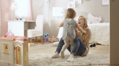 Sevimli küçük kız genç annesi doğru çalışır ve onlar sarıl. Çocuk odası pembe, duvar çizimleri vardır ve tam Toys. Ağır çekim.