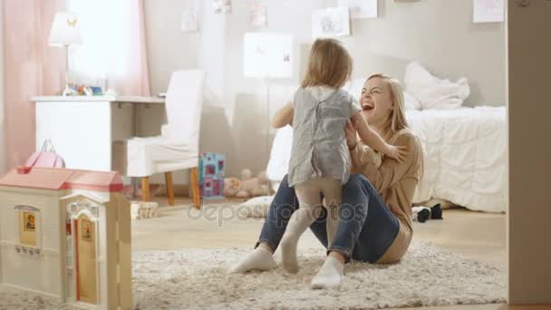 Menina bonito corre para sua jovem mãe e eles abraçam. Quarto infantil é rosa, tem desenhos na parede e é cheio de brinquedos. Movimento lento . — Vídeo de Stock