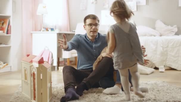Милая маленькая девочка бежит к матери и отцу, и они обнимают её. Детская комната розовая, имеет рисунки на стене и полна игрушек. Slow Motion . — стоковое видео