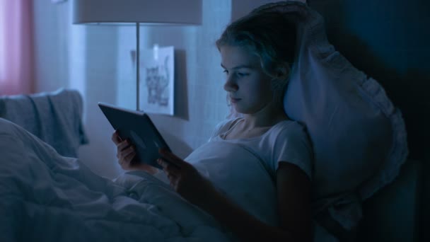 Jonge tienermeisje ligt in haar Bed at Night met Tablet PC. Horloges Tv-Show. — Stockvideo