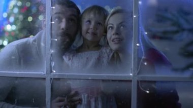 Noel Baba, anne ve sevimli görünüşleri karlı, donmuş bir pencere ve gülümseme.