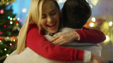 Mutlu güzel kadın onu yakışıklı adam Noel ağacı ve uçan konfeti arka planda Hugs.