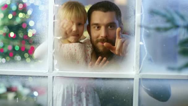 Na véspera de Natal Pai e sua filha bonito olha através do nevado, janela congelada e sorriso . — Vídeo de Stock