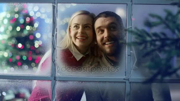 Op kerstavond horloges Beautiful Couple Fireworks door hun bevroren raam met lichten op het. — Stockvideo