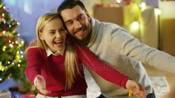 A karácsony boldog szülők ölelés a karácsonyfa alatt, aranyos, kis lányuk. — Stock videók