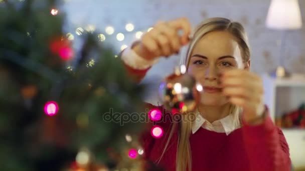 Beautiful Woman Decorates Christmas Tree with Ball Ornament. — Stock Video