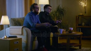 Akşam iki arkadaş salon ve rekabetçi Video oyunları oynarken bir kanepede oturuyor.